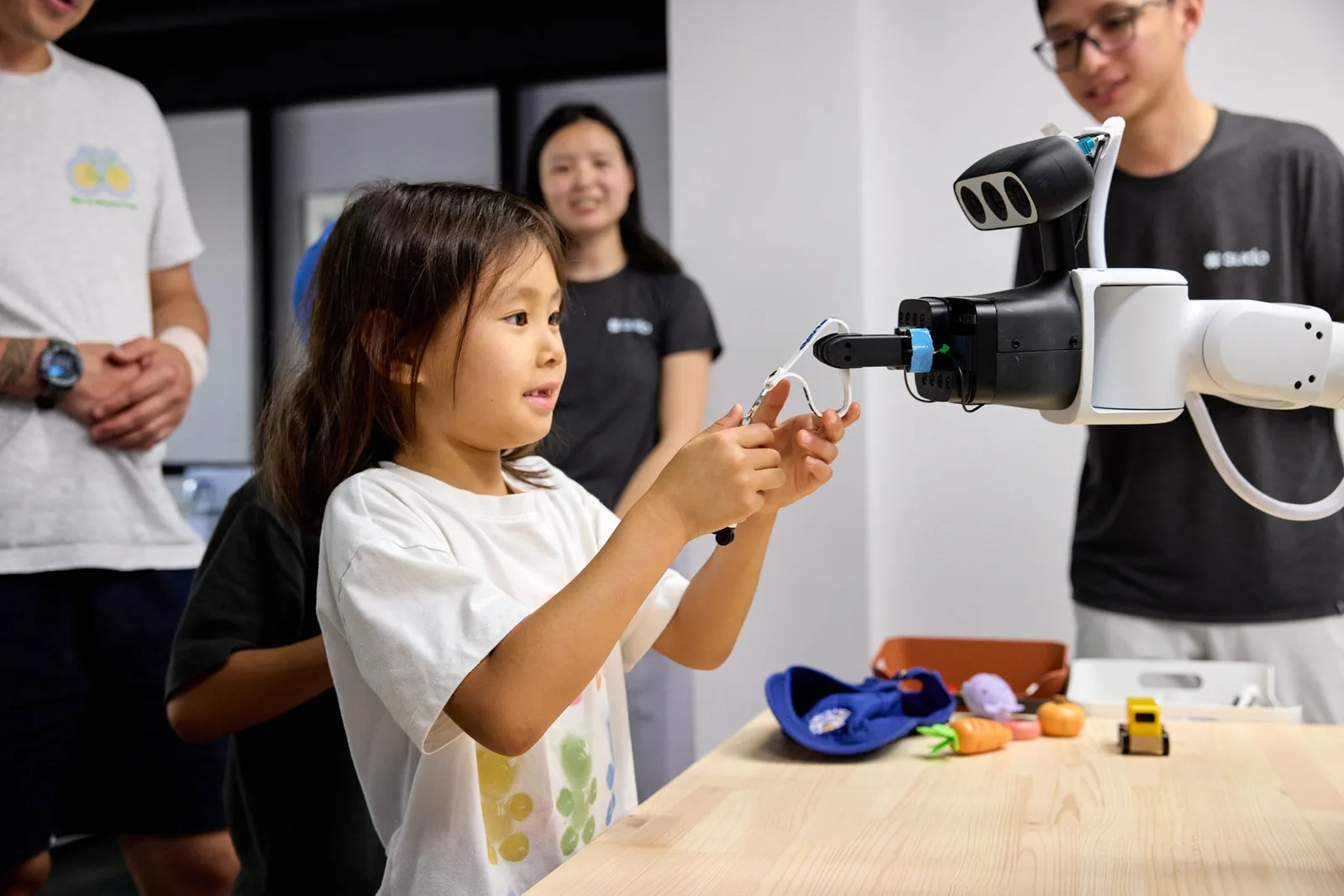 A young visitor hands an object to a robot gripper at bothaus